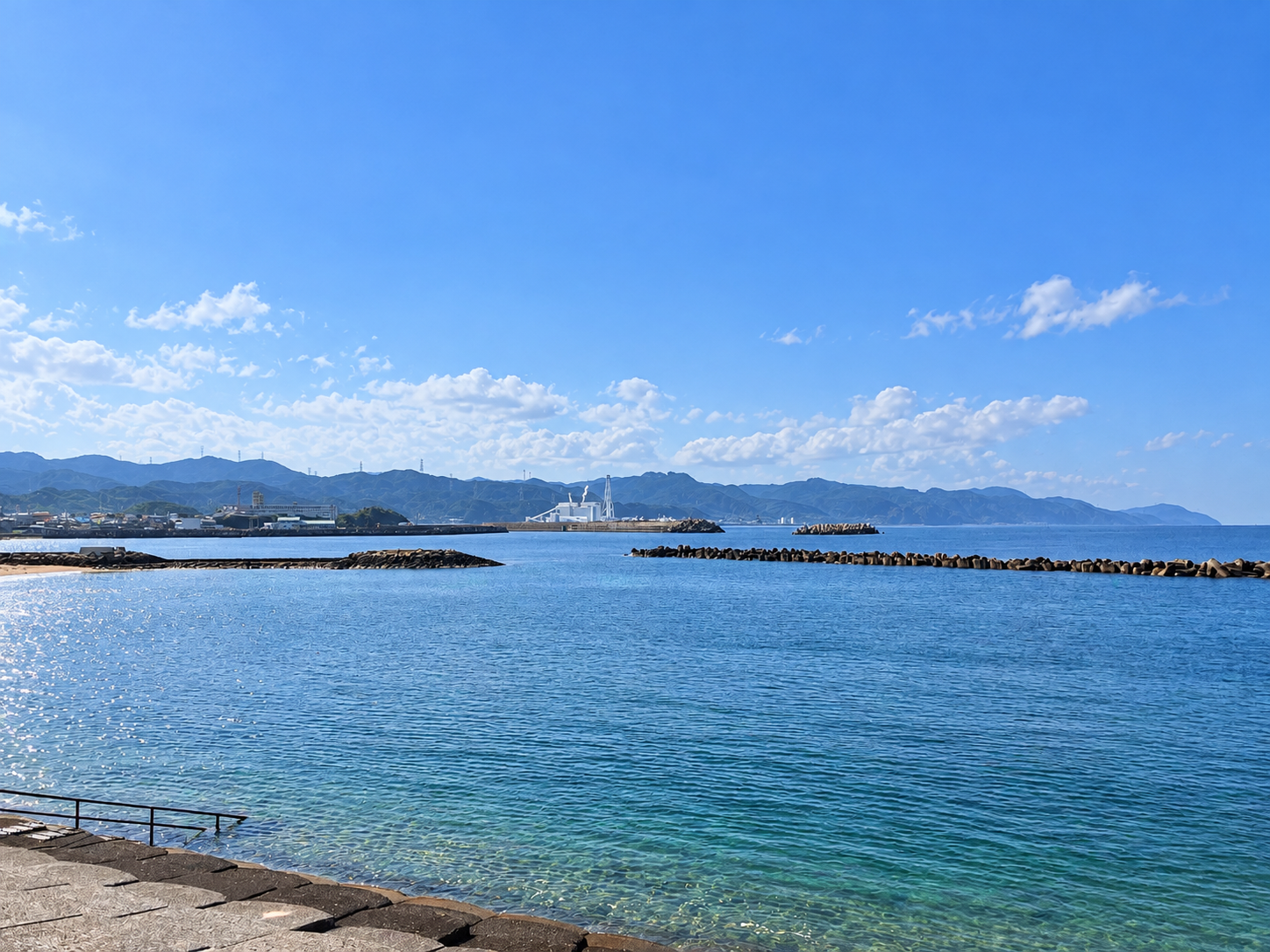 おだやかな青い湾と向こう岸の山並みのAI生成イメージ